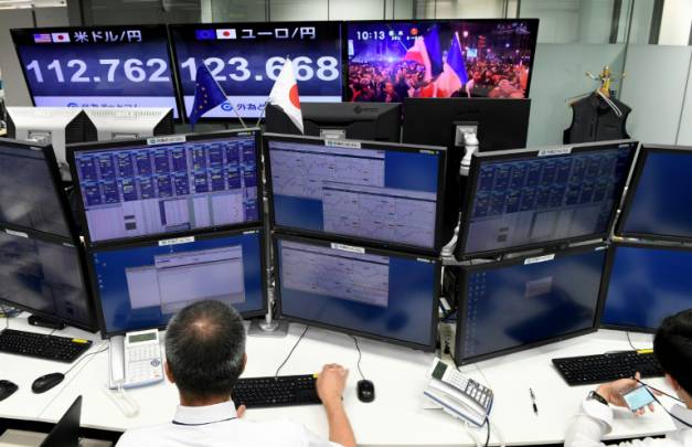 Des courtiers suivent à la télévision la retransmission de l'élection d'Emmanuel Macron à la présidence de la République à la Bourse de Tokyo, le 8 mai 2017 ( AFP / Toshifumi KITAMURA )